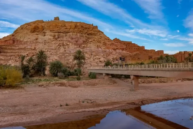 View of the bridge entrance leading to the ancient fortress of Ait Benhaddou, a highlight of a luxury tour in Morocco.