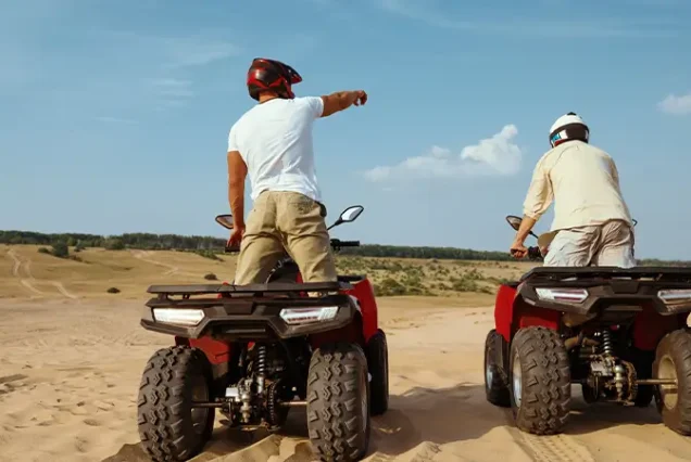 Friends enjoying an exhilarating quad bike experience through the Merzouga desert dunes on a luxury Morocco tour.