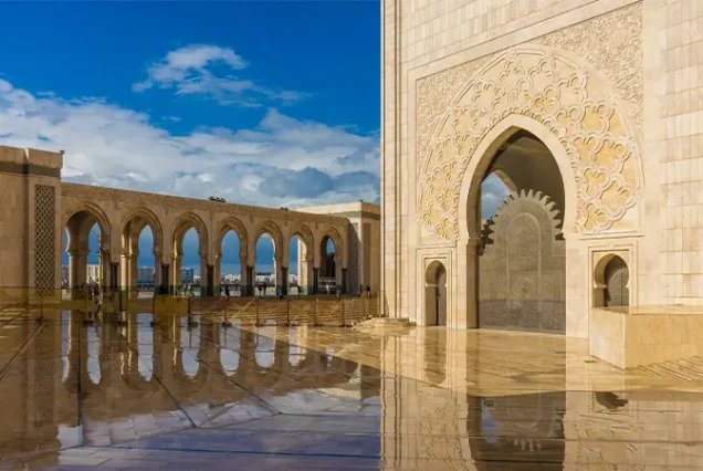 The stunning reflection of the Hassan II Mosque's intricate architecture captured on the glossy marble flooring, highlighting its grandeur under soft lighting.